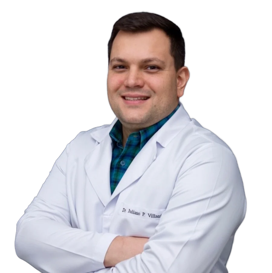 Dr. Juliano Villani, de jaleco branco, sorrindo de braços cruzados